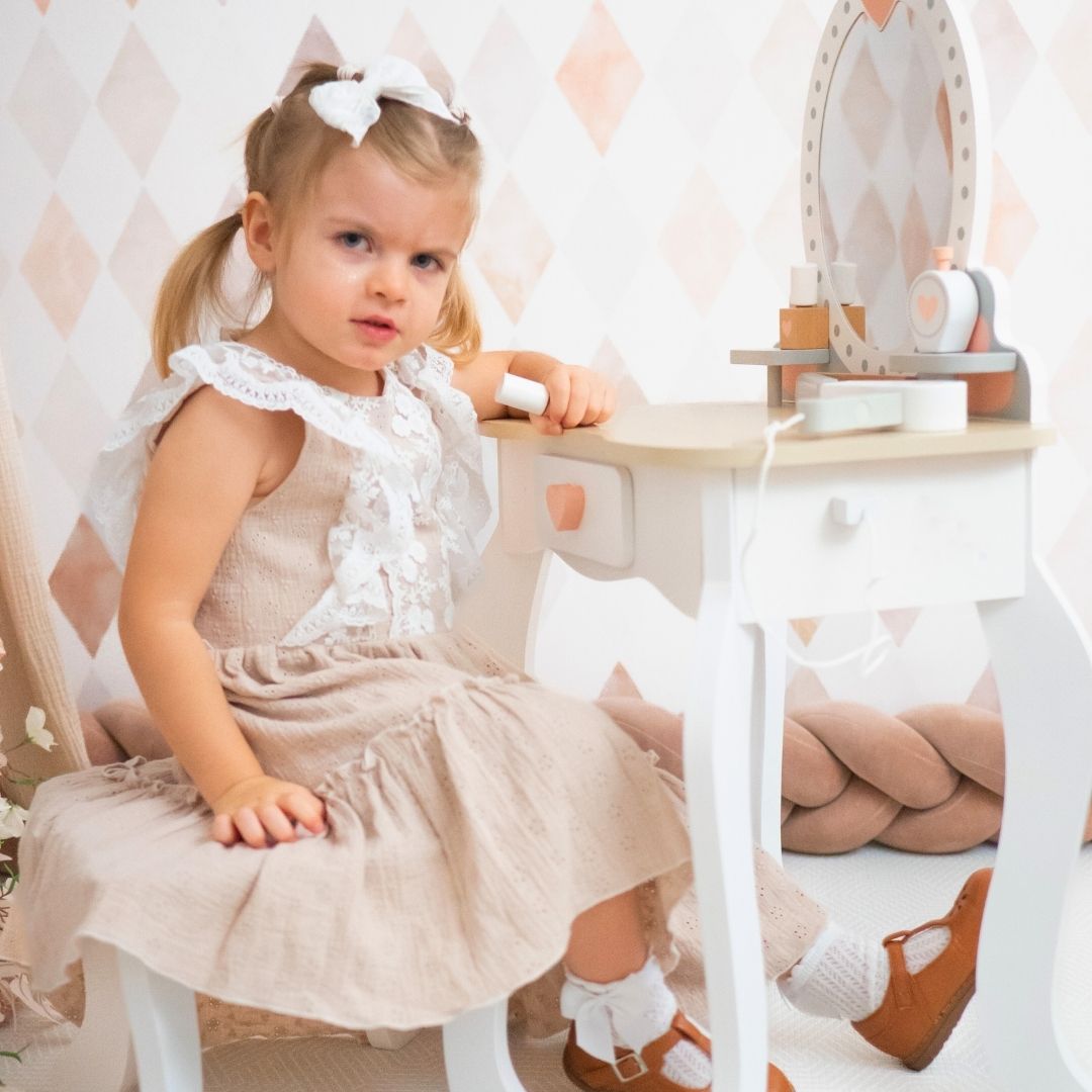 Tocador de madera con taburete y accesorios.