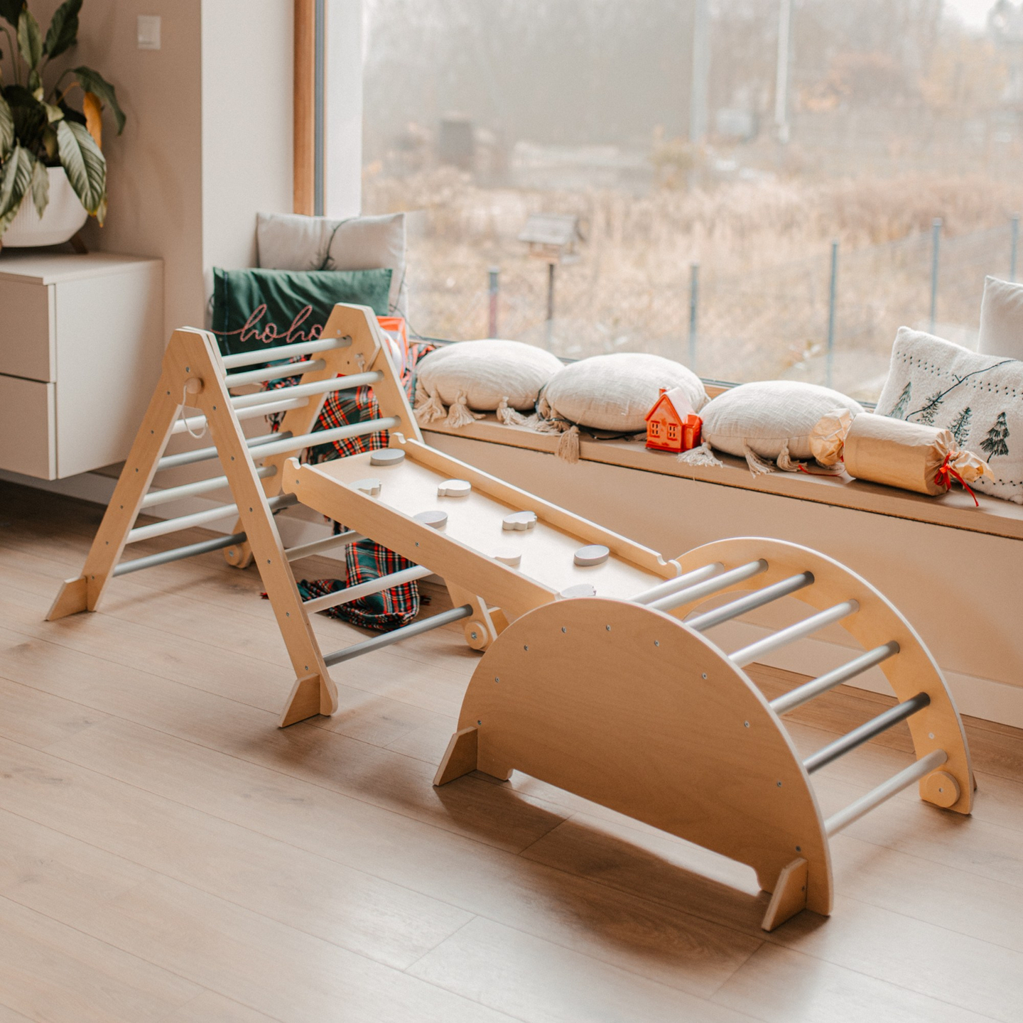 Parque infantil interior de madera con muro de escalada, tobogán, arco de escalada/balancín y triángulo de Pikler.
