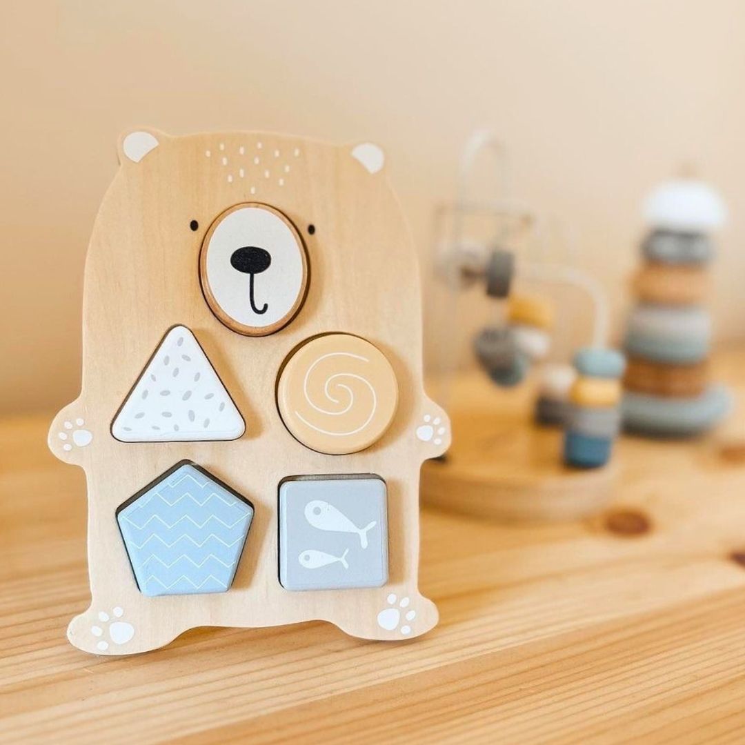 Un juego de juguetes de madera: un entrelazado de colores, una pirámide de focas y un clasificador de ositos de peluche.