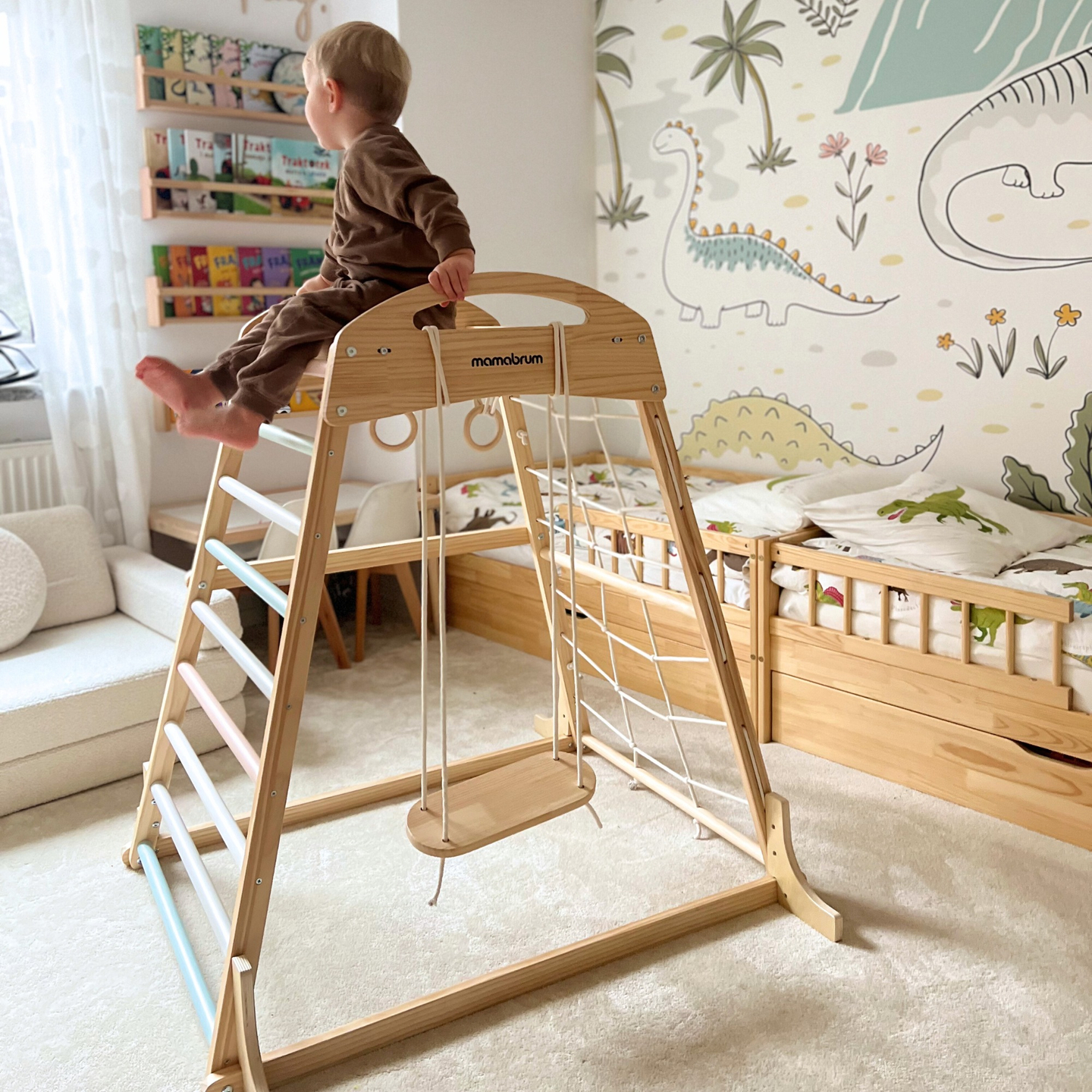 Parque infantil interior de madera con columpio, anillos de gimnasia y red de escalada.